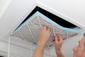 image of a homeowner replacing an hvac air filter to improve indoor air quality Feel the Difference with Our Award-Winning HVAC Team
