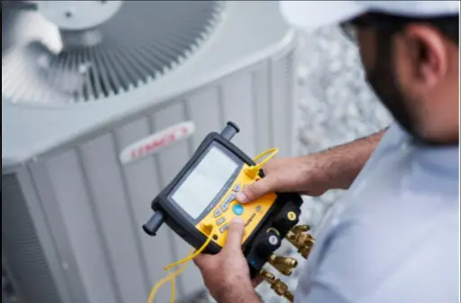 Technician using diagnostic equipment on an air conditioning unit.