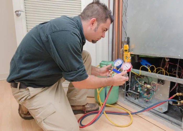 A technician repairs an air conditioner, showcasing HVAC expertise in Oklahoma City, OK, by The Chill Brothers.