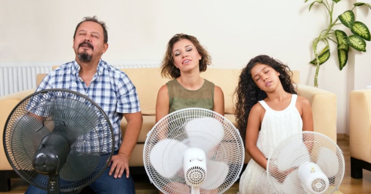 Family overheated in the living room using electric fans during a heatwave
